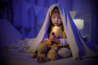 © DN6 - Child asian girl playing teddy bear with flashlight under the blanket on bed in a dark bedroom at night before sleeping, Comfortable children at home concept