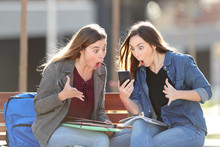 Two Amazed Students Checking Phone Content In A Park