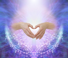 Poster - Healers hands making a humble heart shape - female hands forming a heart shape against a pink circle surrounded by ethereal blue and beautiful glittering sparkles with copy space above