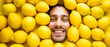 canvas print picture - Mann mit Zitronen, Konzept für die Lebensmittelindustrie. Gesicht des lachenden Mannes in der Zitronenoberfläche.