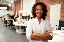 Portrait Of Businesswoman In Modern Open Plan Office With Business Team Working In Background
