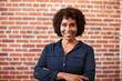Portrait Of Smiling Mature Businesswoman Standing Against Brick Wall In Modern Office