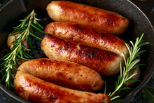 Freshly Cooked Butchers Made, Homemade Sausages With Rosemary In Cast Iron Frying Pan