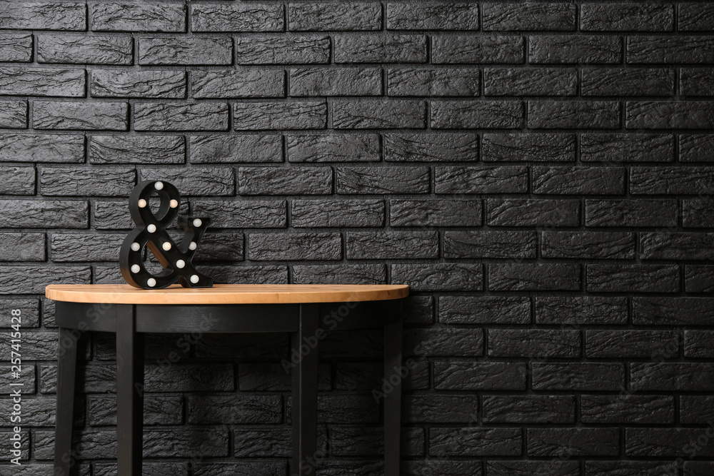 Modern table near dark brick wall