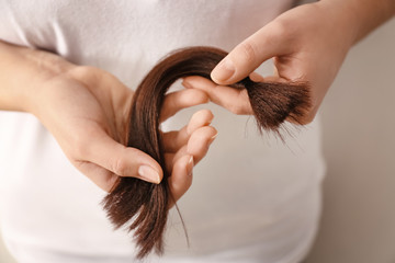 Woman with hair strand on light background, closeup. Concept of donation