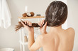 Woman using coconut oil for hair in bathroom