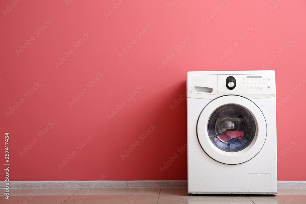 Modern washing machine near color wall