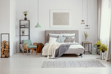 Sticker - Grey and pastel bedroom design with big comfortable bed with lot of pillows and cozy blankets and abstract silver painting on the wall, real photo