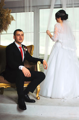 wedding photoshoot in the Studio. the bride and groom posing. groom with a red tie and black business suit. the bride in a white lush dress