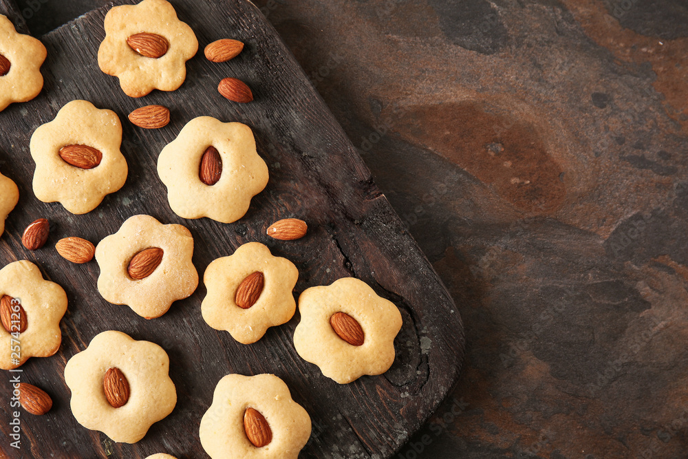 Wooden board with tasty cookies on dark table