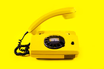 Retro vintage phone handset plastic yellow disko background old style 90 telephone answer call raised