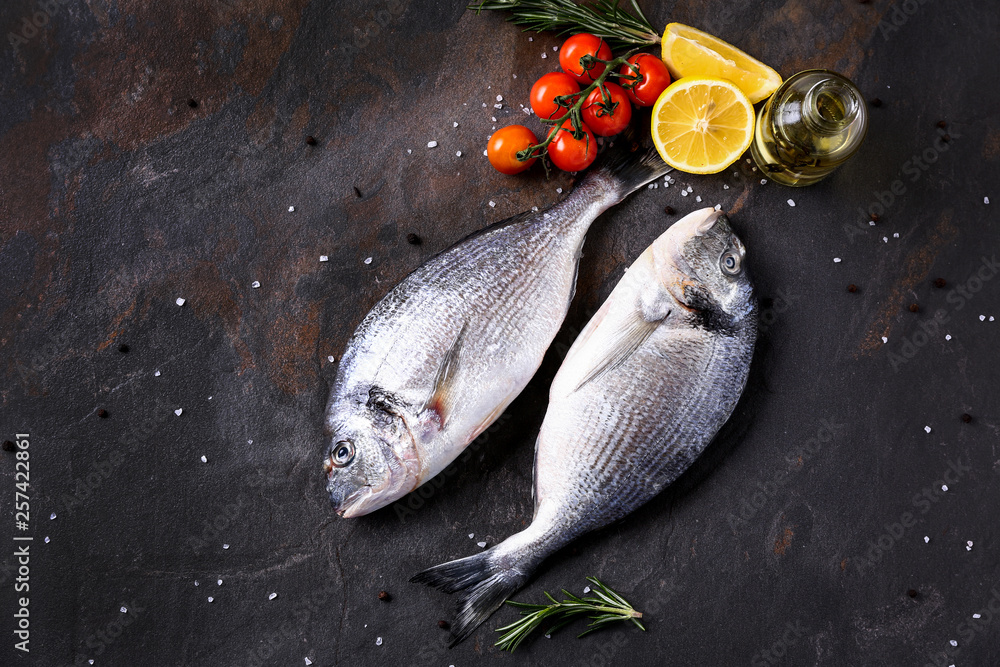Fresh fish, tomato and lemon on table