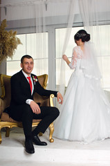 wedding photoshoot in the Studio. the bride and groom posing. groom with a red tie and black business suit. the bride in a white lush dress