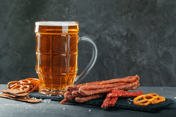  beer and appetizing beer snacks set. Table with mug of beer, wooden board with sausages