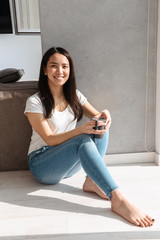 Sticker - Smiling asian woman holding cup of coffee while