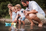 Young family with two toddler children outdoors by the river in summer, playing.