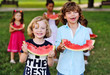 © Evgeniy Kalinovskiy - two cheerful children of boys with curly hair eat a ripe juicy watermelon in the Park with friends and smile
