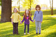 © Evgeniy Kalinovskiy - a group of small children smiling holding hands on a background of grass, a tree and a park. Children's Day, June 1, friendship, childhood.