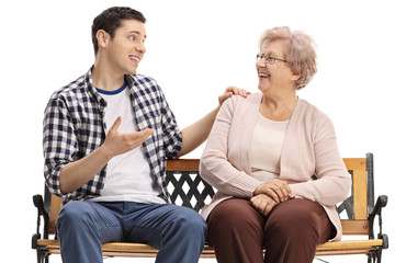 Young guy and a senior woman sitting on a bench and talking