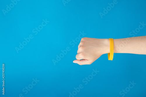 Fotomural Female hand with empty yellow bracelet on blue background
