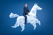 © gearstd - Young businessman riding white cloud horse on blue background