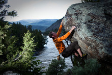 A Athletic Man Bouldering Above A River Near Bozeman, Montana.