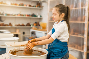 Wall Mural - beautiful little girl making a pot of clay in a pottery workshop