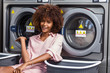 © Samuel B. - Young black African American woman waiting her clothes to be washed in a automatic laundry