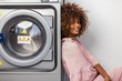 © Samuel B. - Young black African American woman waiting her clothes to be washed in a automatic laundry