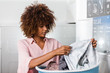 © Samuel B. - Young black African American woman holding a basket of clothes to be washed in a automatic laundry