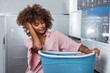 © Samuel B. - Young black African American woman holding a basket of clothes to be washed in a automatic laundry