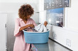 © Samuel B. - Young black African American woman holding a basket of clothes to be washed in a automatic laundry