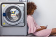 © Samuel B. - Young black African American woman waiting her clothes to be washed in a automatic laundry