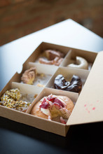 A Box Of Donuts Sit In The Natural Light Of An Office.