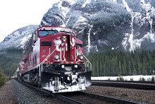 Freight Train Passing By Forest Against Snowcapped Mountains