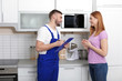 © New Africa - Housewife and repairman near microwave oven in kitchen
