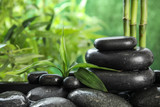 Fototapeta Desenie - Zen stones and bamboo leaves in water on blurred background. Space for text