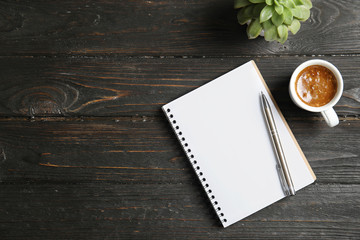 Wall Mural - Notebook, coffee and plant on dark wooden background. Space for text