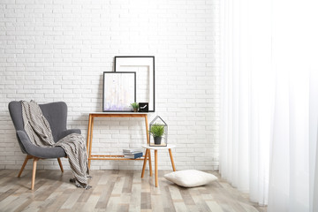 Canvas Print - Stylish living room interior with comfortable armchair near brick wall. Space for text