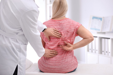 Sticker - Chiropractor examining patient with back pain in clinic