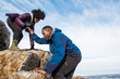 © Cavan Images - Woman helping man up rock outcrop