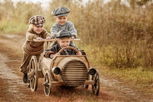 Children Ride On A Makeshift Wooden Racing Car