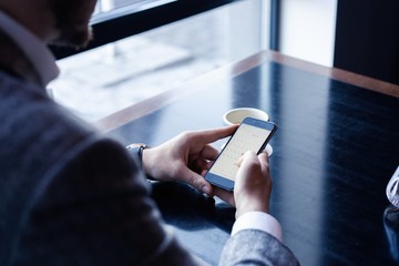 Canvas Print - Modern businessman drinking espresso coffee in the cafe during lunch time and using mobile phone.