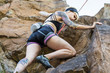 © Cavan Images - Tattooed girl rock climbing with friend on summer day