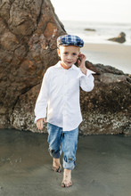 Portrait Of Boy Wearing White Shirt And Flat Cap On Beach