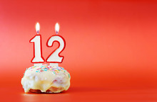Twelve Years Birthday. Cupcake With White Burning Candle In The Form Of Number 12. Vivid Red Background With Copy Space