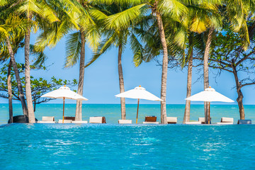 Umbrella and chair around swimming pool in hotel resort neary sea ocean beach for vacation