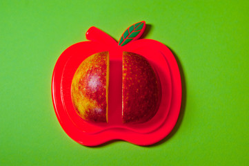  Two slices of red apple lying on a cutting board shot large against an orange background