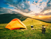 Tourist Camp In Mountains With Tent And Cauldron Over Fire At Sunset