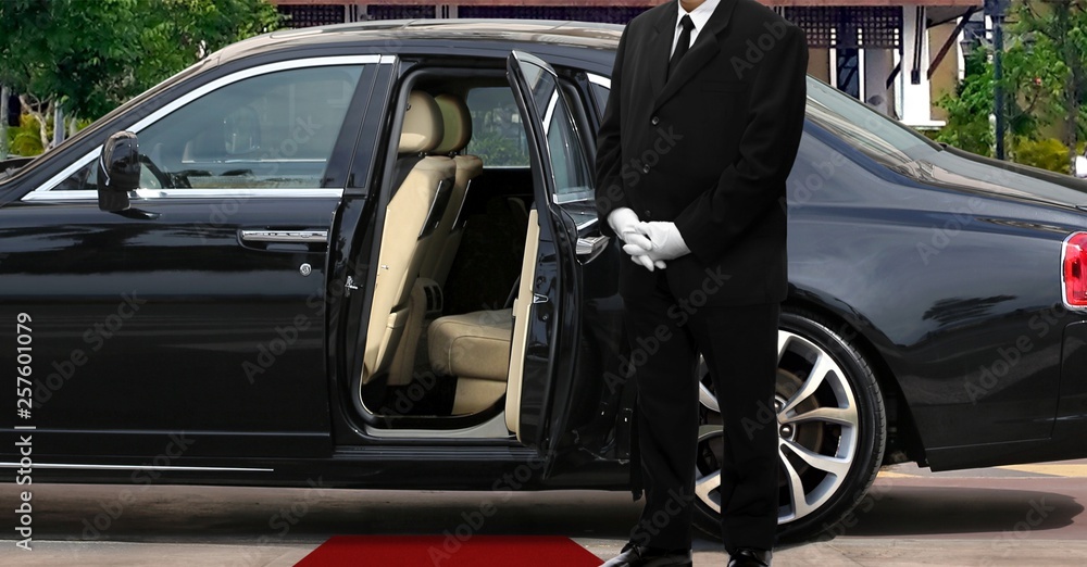 Limo driver standing next to opened car door with red carpet - obrazy, fototapety, plakaty 